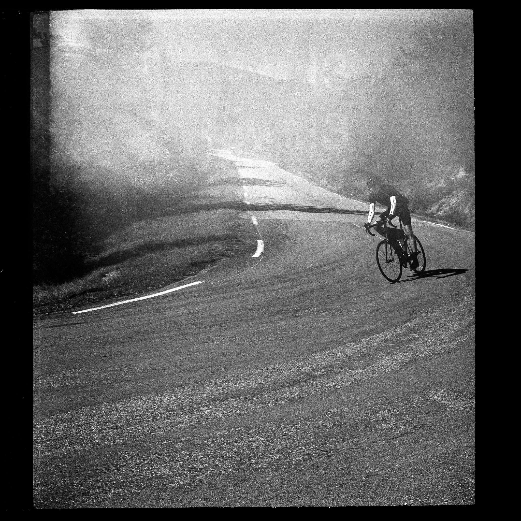 a cyclist in a sharp downhill corner in high grain analog black and white